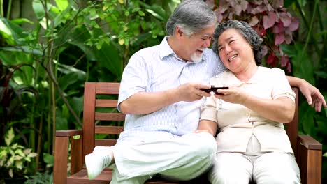 Senior-couple-sitting-and-drinking-red-wine-together-in-home-garden.