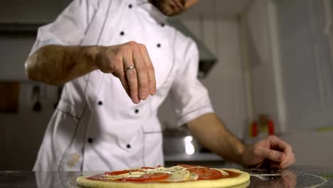 The-chef-sprinkles-spices-on-the-finished-pizza-in-the-kitchen