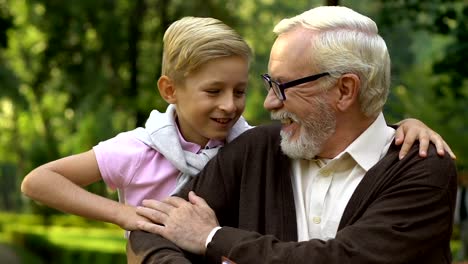 Lindo-niño-sentado-sobre-un-banco-cerca-de-abuelo-mostrándole-fotos-familiares