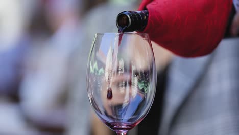 Rotwein.-Kellner-gießt-Wein-im-Glas-im-Restaurant-Closeup