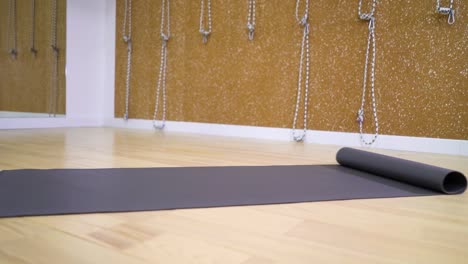 view-of-young-woman-feet-and-hands-unrolling-mat-in-fitness-studio