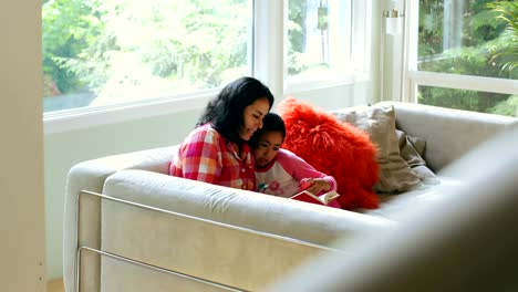 Mother-and-daughter-reading-book-in-living-room-4k