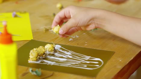 Close-up-de-niña-haciendo-papel-craft-con-flores-secas