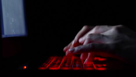 Hacker-Mädchen-Hand-tippen-auf-Tastatur-mit-roter-Hintergrundbeleuchtung