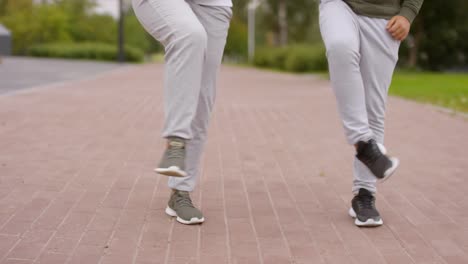 Piernas-de-madre-e-hijo-haciendo-ejercicio-de-rotación-de-rodilla-al-aire-libre