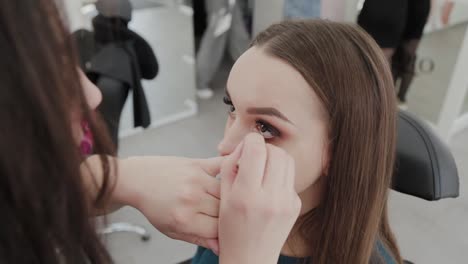 Professionelle-Make-up-Künstler-Frau-malt-Wimpern-an-Kunden-des-Schönheitssalons