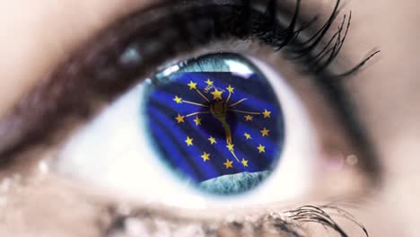 Woman-blue-eye-in-close-up-with-the-flag-of-Indiana-state-in-iris,-united-states-of-america-with-wind-motion.-video-concept