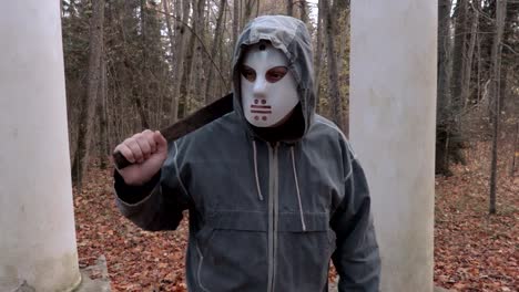 Camera-is-approaching-man-in-scary-Halloween-mask-and-machete