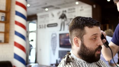 Hairdresser-makes-hairstyle-to-a-young-bearded-man