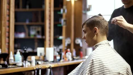 Professional-stylist-makes-modern-haircut-for-young-guy