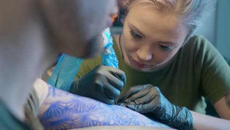 mujer,-un-artista-del-tatuaje,-hace-un-tatuaje-en-el-salón.