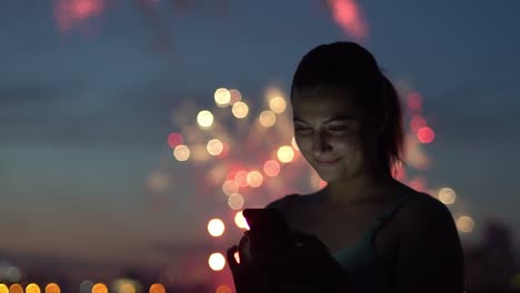 Eine-Mädchen-nutzt-eine-Smartphone-während-ein-Feuerwerk