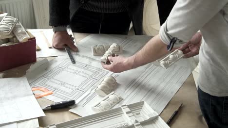 Hands-of-male-sculprot-and-architector-comparing-white-plaster