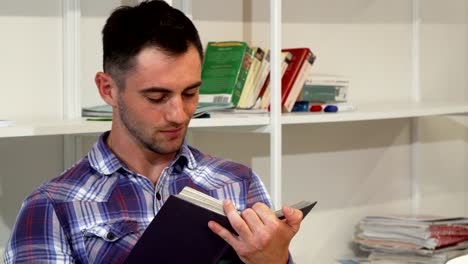 Handsome-young-man-smiling-joyfully-while-reading-a-book