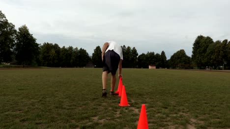 Coach-places-red-cones-on-the-football-field