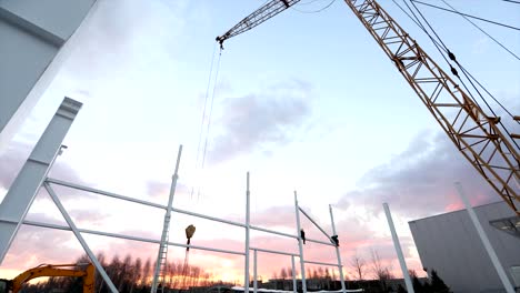 Industrial-exterior,-Mounting-of-metal-structures-against-the-background-of-an-orange-sky-with-clouds