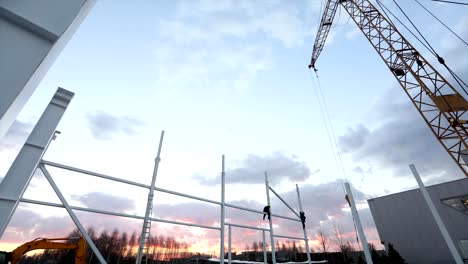 Industrial-exterior,-Mounting-of-metal-structures-against-the-background-of-an-orange-sky-with-clouds