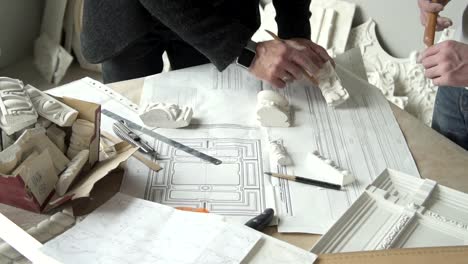 Hands-of-two-male-architects-working-with-white-plaster