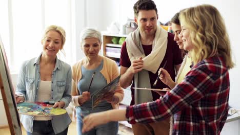 group-of-artists-discussing-painting-at-art-school