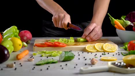 Man-is-cutting-vegetables-in-the-kitchen,-slicing-green-bell-pepper-in-slow-motion