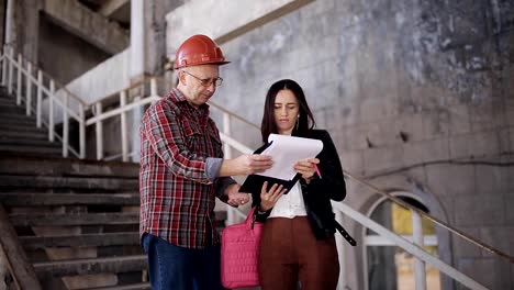 El-ingeniero-de-la-mujer-y-el-capataz-en-casco-compare-adquirida-para-la-construcción-de-la-declaración-y-confirman-la-fecha-de-entrega-del-objeto.