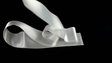 Satin-ribbon-on-a-black-background.-Slow-motion.