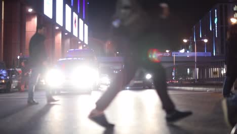Fußgänger-überqueren-der-Straße-in-der-Nacht-bei-120fps-slow-Motion.-Lens-Flares-von-Autos-im-Hintergrund-mit-Menschenmenge-im-Vordergrund
