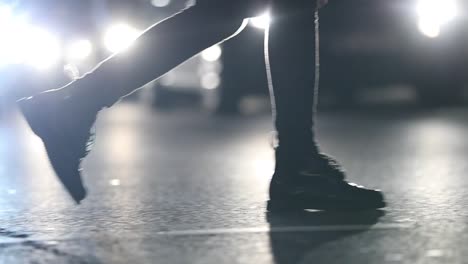 Pedestrians-feet-crossing-street-at-night-with-lens-flares-hitting-camer-ain-the-background