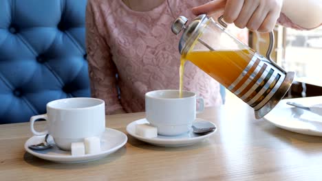 Mujer-joven-vierte-té-de-frutas-en-tazas-en-un-café