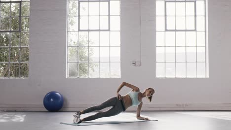 Mujer-haciendo-ejercicios-de-tablas-de-lado-en-el-gimnasio