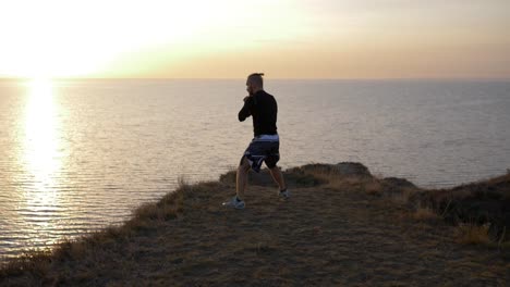 self-defense-training,-boxer-male-practicing-fist-fight-before-competition-on-hill-near-sea