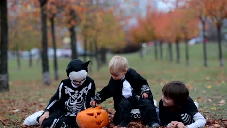 Kinder-Spaß-mit-Halloween-geschnitzten-Kürbis-in-einem-Park,-gruselige-Kostüme-tragen-und-spielen-mit-Spielzeug