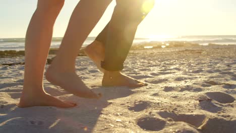 Sección-baja-de-pareja-caminando-en-la-playa-en-un-día-soleado-4k