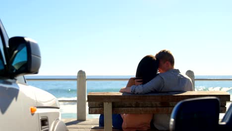 Rear-view-of-couple-sitting-on-bench-near-railings-4k