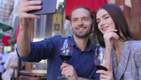 Feliz-pareja-con-vino-tomando-fotos-en-el-teléfono-en-el-restaurante