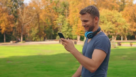 gut-aussehender-Mann-Spaziergänge-nutzen-mobile-im-freien