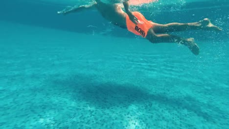 Junger-Mann-schwimmt-unter-Wasser-in-einem-Schwimmbad