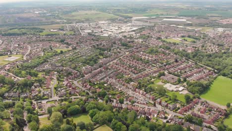 Imágenes-aéreas-con-vistas-a-la-ciudad-británica-de-Castleford-cerca-de-Wakefield-en-West-Yorkshire,-mostrando-filas-de-casas-y-campos-en-el-fondo,-tomadas-en-un-soleado-día-de-verano-brillante.