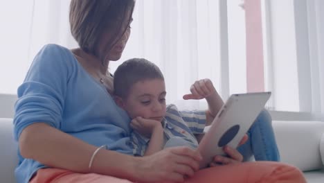 Mutter-und-Sohn-spielen-mit-digitalen-Tablet-zu-Hause.-Junge-Mutter-mit-ihrem-5-Jahre-alt-lächelnd-mit-digitalen-Tablet-zu-Hause.