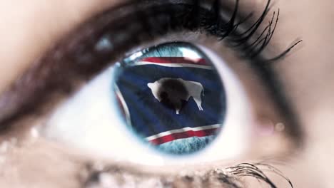 Woman-blue-eye-in-close-up-with-the-flag-of-Wyoming-state-in-iris,-united-states-of-america-with-wind-motion.-video-concept