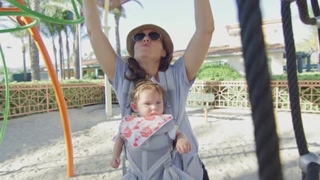 Frau-genießt-Spielplatz-mit-ihrem-Baby-in-einem-Träger