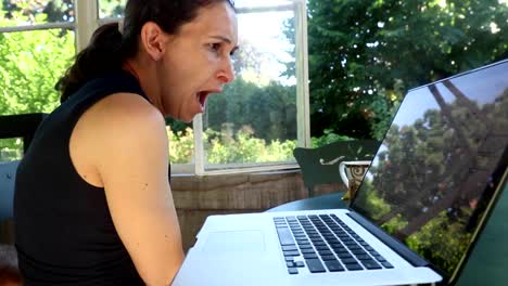 Casual-candid-shot-of-woman-yawning-in-front-her-computer-screen.-Woman-in-her-30s-working-from-her-balcony-home.