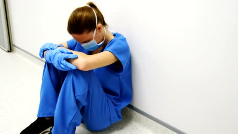 Tensed-female-doctor-sitting-in-corridor