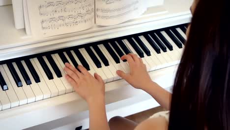 Young-brunette-is-playing-the-piano-in-bright-room