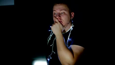 Sad-young-man-with-christmas-garland-using-computer