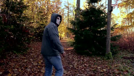 Man-with-Halloween-mask-and-machete-alone-on-path-in-park