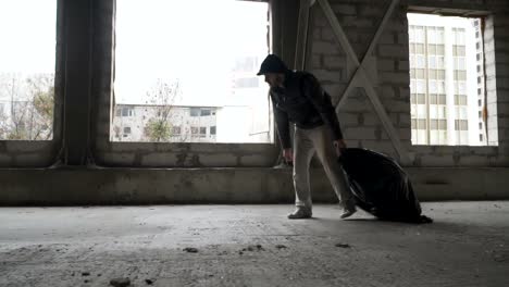 Dirty-homeless-drags-a-garbage-bag-in-abandoned-building