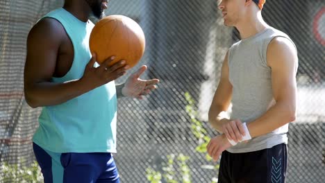 Zwei-sportliche-multirassische-Freunde-diskutieren-letzten-Basketball-Spiel-im-Stadion