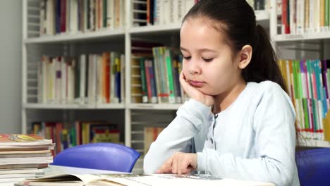 Niedliche-kleine-Mädchen-träumen-beim-Lesen-eines-Buches-in-der-Bibliothek
