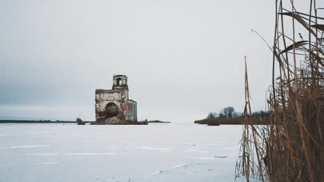 Verlassene-Kirchengebäude-in-der-Mitte-des-zugefrorenen-See-mit-Schnee-bedeckt